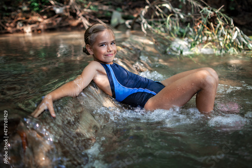 Happy girl resting on rapids in stream canyon river in the mountains, nature pool. Cold water, hardening and natural spa procedure, wildlife and green tourism, summer holidays