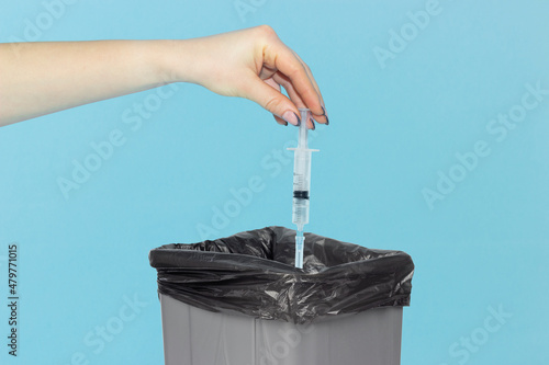 Fotografi spitz in the trash bin, syringe in hand in front of the trash bin, concept of re