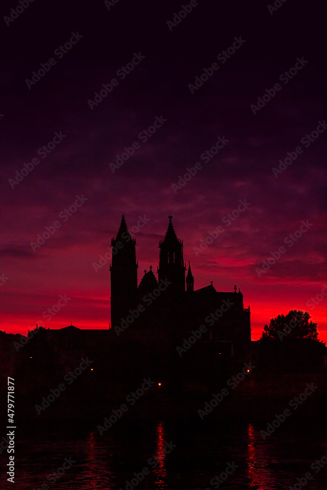 Cover page with silhouettes of a medieval castle, cathedral at beautiful bloody sunset at historical downtown of Magdeburg, old town, Elbe river with copy space for text, Germany.