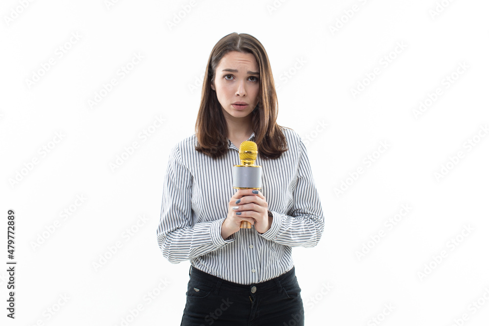 The girl is shy to sing into the microphone. Photo on a white background The girl is shy to sing into the microphone. Photo on a white background