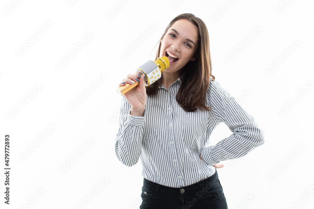 Smiling brunette sings into a microphone on a white background Smiling brunette sings into a microphone on a white background