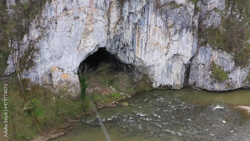 Aerial view of a cave entrance and mountain river. Unguru Mare cave, Suncuius, Romania photo