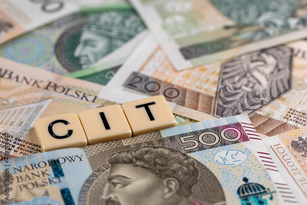 The wording "CIT" translated as Company Income Tax" plus many Polish banknotes. New tax rules in Poland at 2022. Photo taken under artificial, soft light - obrazy, fototapety, plakaty 