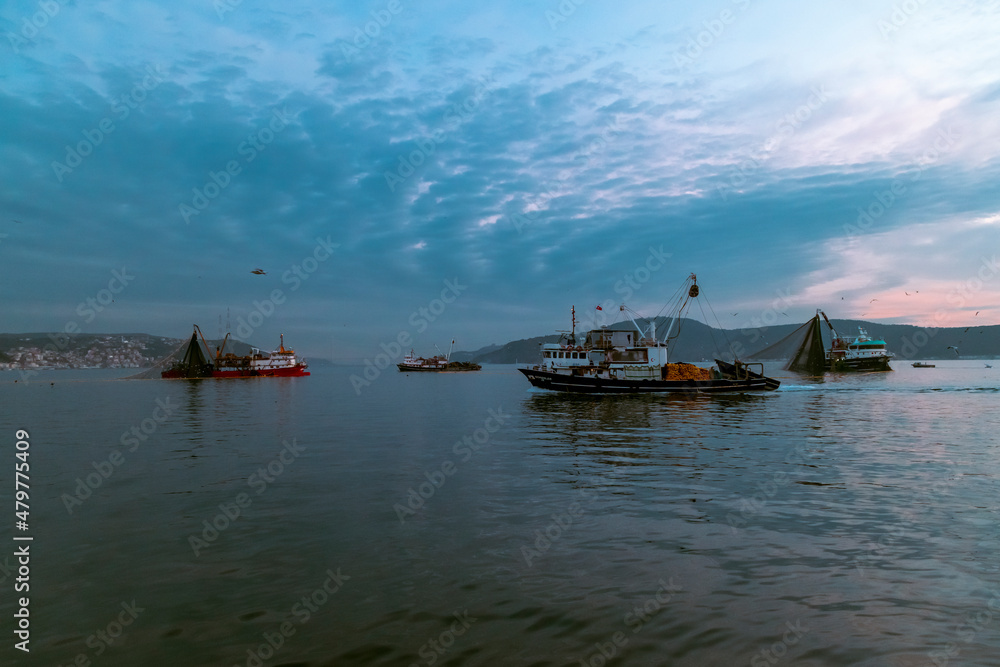 fisherman fishing boats on Bosporus Istanbul on a Foggy sunrise. Rainy clouds and dark weather. seagulls flying over the sea fisherman fishing boats on Bosporus Istanbul on a Foggy sunrise. Rainy clouds and dark weather. seagulls flying over the sea