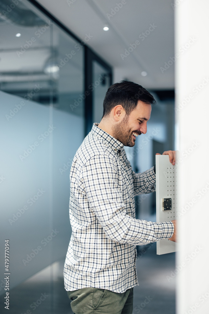 Happy caucasian man, smiling and opening a metal locker door.