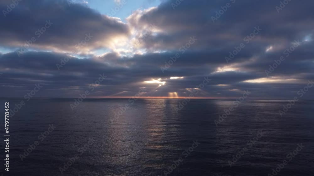 Drone view of sun rays peaking through thick dark clouds over the ocean in the evening. can be used for cinematography, establishing shot or in a motivational video. Drone view of sun rays peaking through thick dark clouds over the ocean in the evening. can be used for cinematography, establishing shot or in a motivational video.