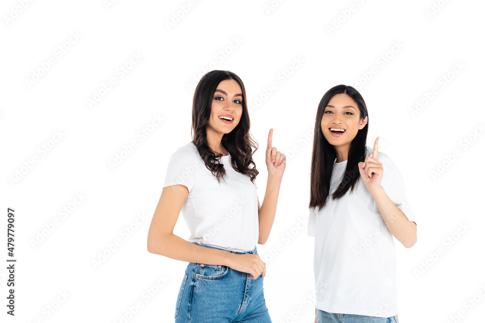 joyful multiethnic women looking at camera and pointing with fingers isolated on white. joyful multiethnic women looking at camera and pointing with fingers isolated on white.