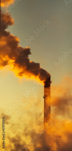 Smoke from a chimney on a winter day against the background of the sky illuminated by the setting sun