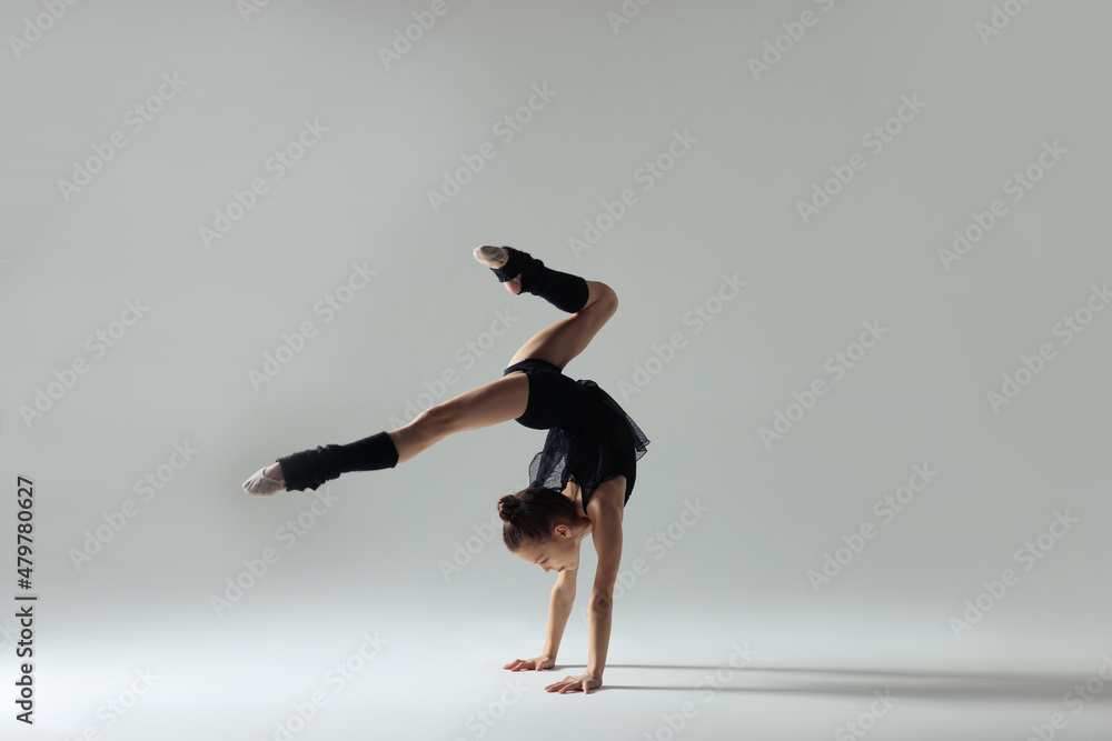 Cute little gymnast doing handstand on white background