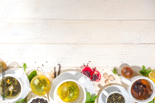 Various tea ball bombs. Assortment of different tea balls with dried tea, cups, lemon and mint, top view copy space. Trendy modern tea variety photo