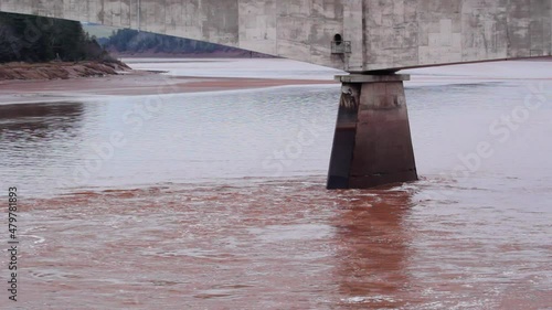 Fast flowing Shubenacadie river and Gosse bridge support in South Maitland, Nova Scotia photo