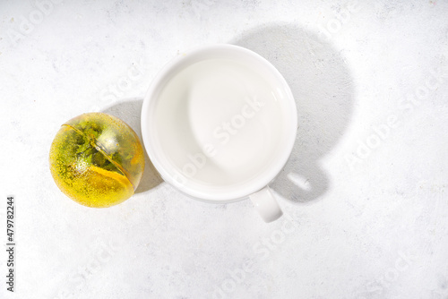 Making tea with Trendy modern tea ball bombs. Tea balls with dried tea, cups, lemon and mint, with classic white cup, top view copy space
