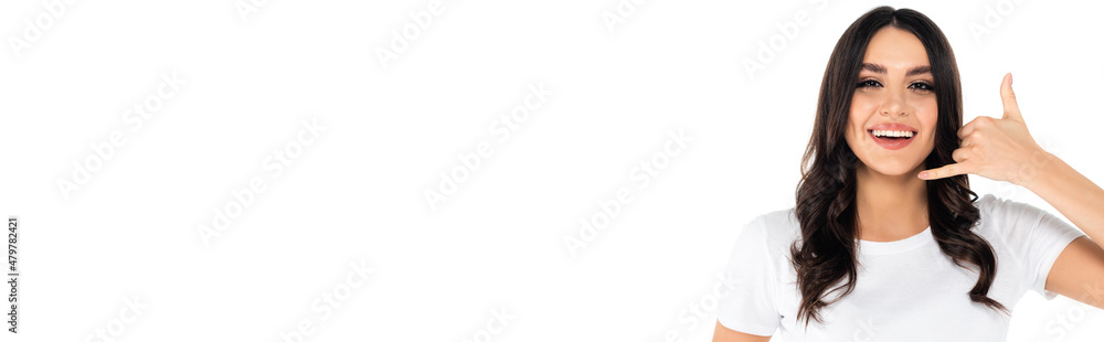 cheerful brunette woman showing call me gesture while looking at camera isolated on white, banner. cheerful brunette woman showing call me gesture while looking at camera isolated on white, banner.