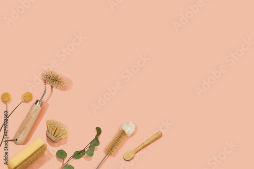 Set of eco friendly zero waste sustainable recyclable cleaning brushes and accessories with green eucalyptus and yellow flower ball on pink background. Alternative household chores. Natural living. © Nastassia Kudzina