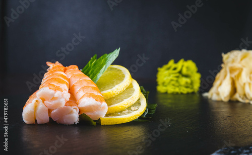 Bowl of Baechu Kimchi or traditional Napa Cabbage Kimchi on wooden table with blurred silver chopsticks, perilla leaves, double handle Korean yellow aluminum pot, eggs, salted and fermented shrimp. photo