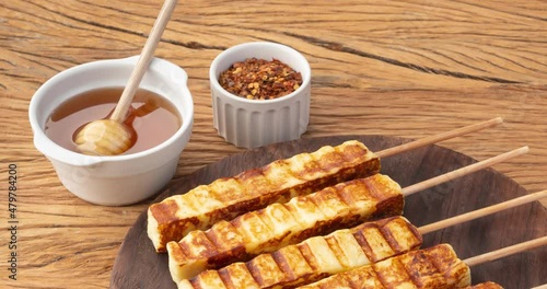 Grilled Rennet or Coalho cheese on a wooden board with sugar syrup and pepper