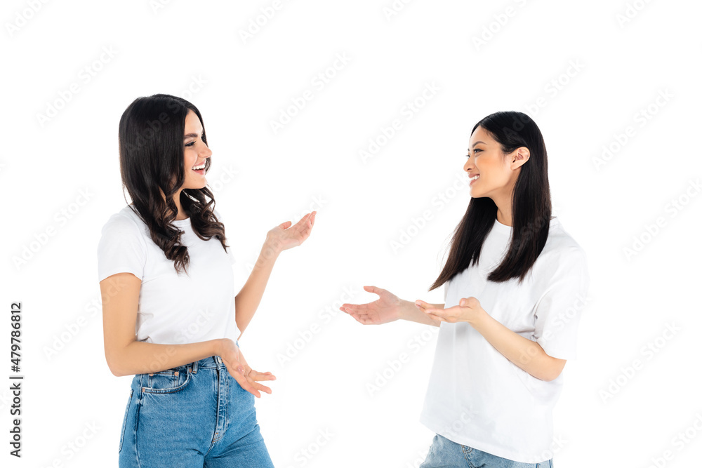cheerful interracial women in t-shirts and jeans talking isolated on white. cheerful interracial women in t-shirts and jeans talking isolated on white.
