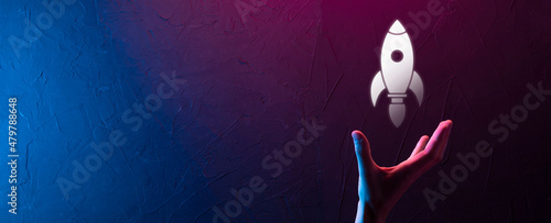 Startup business concept, Businessman holding tablet and icon rocket is launching and soar flying out from screen with network connection on dark background.