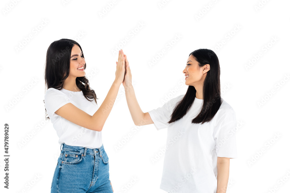 cheerful multiethnic women in t-shirts giving high five isolated on white. cheerful multiethnic women in t-shirts giving high five isolated on white.