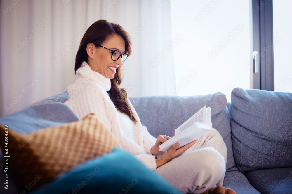 Attractive woman reading a book while relaxing at home Attractive woman reading a book while relaxing at home