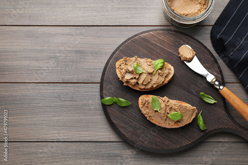 Slices of bread with delicious pate and basil on wooden table, flat lay. Space for text