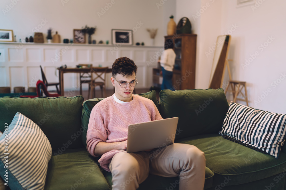 Man with laptop on sofa with blur of girl at home Man with laptop on sofa with blur of girl at home