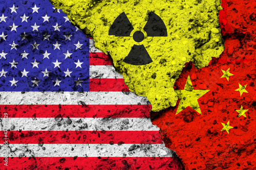 Concept of the Relationship between the United States of America (USA) and China on nuclear policy issues with flags and a radiation hazard sign painted on a rough wall
