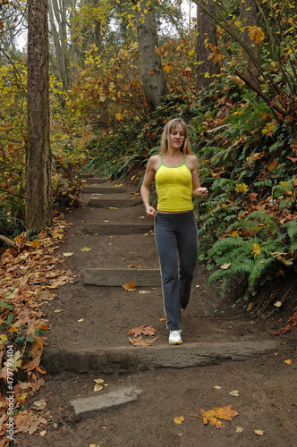Woman jogging in forest trail downhill with steps, Washington state, USA, MR