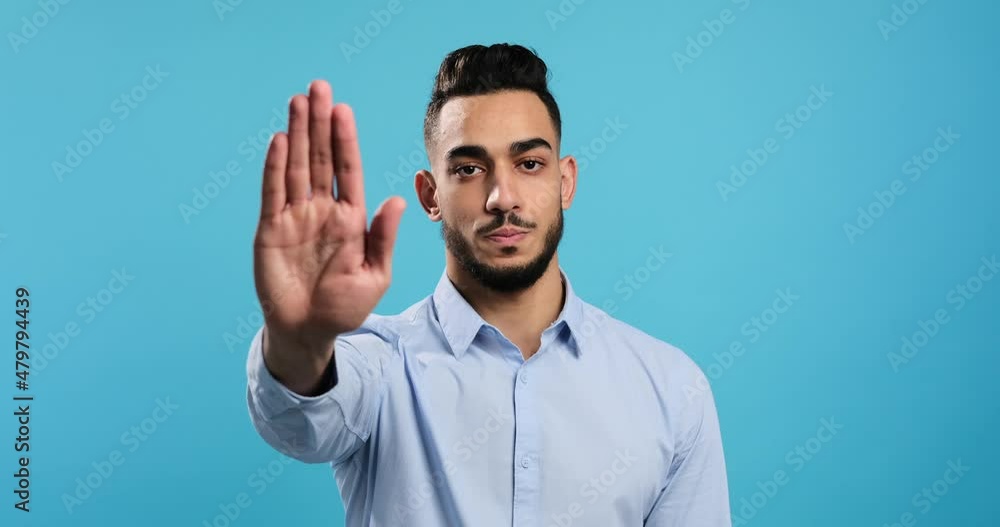 Portrait of businessman saying no with stop hand sign over blue background Portrait of businessman saying no with stop hand sign over blue background