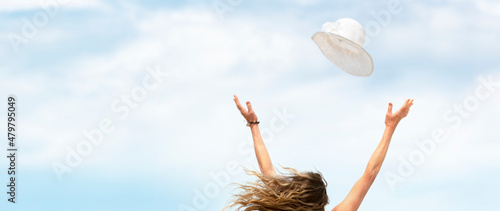 Fotografia Fliegender sonnenhut mit ausgestreckten Armen einer Frau vor Himmel