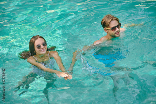 Young couple swimming in a pool and feeling excited