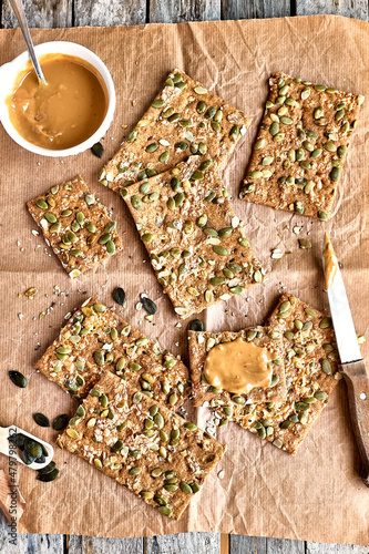 Crunchy crispbread and peanut butter on wooden table. Whole Grain crisp bread with pumpkin, sunflower, chia, linen and sesame seeds. Healthy snack. Bio-organic dieting product. photo