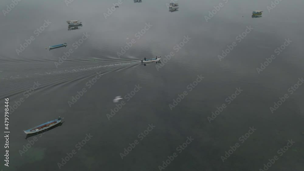 Circling a moving fishing boat passing through other boats in calm water. Aerial shot in smooth movement. Birds flying around. Circling a moving fishing boat passing through other boats in calm water. Aerial shot in smooth movement. Birds flying around.