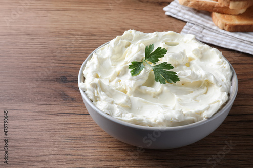 Tasty cream cheese with parsley on wooden table. Space for text