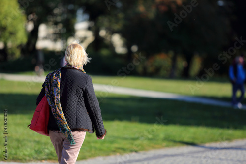 Kobieta z torebką spaceruje w parku we Wrocławiu.