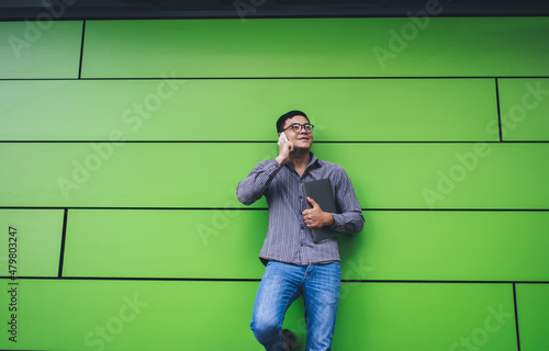 Guy talking on smartphone on green wall background