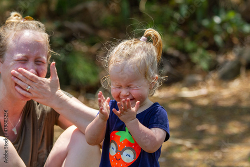 Mother and toddler daughter laughing hysterically in backyard. photo