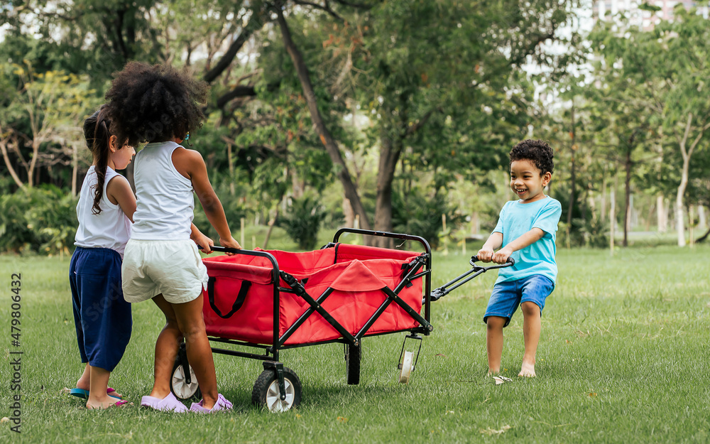 Mixed race little cute children pull and drag a red cart while playing