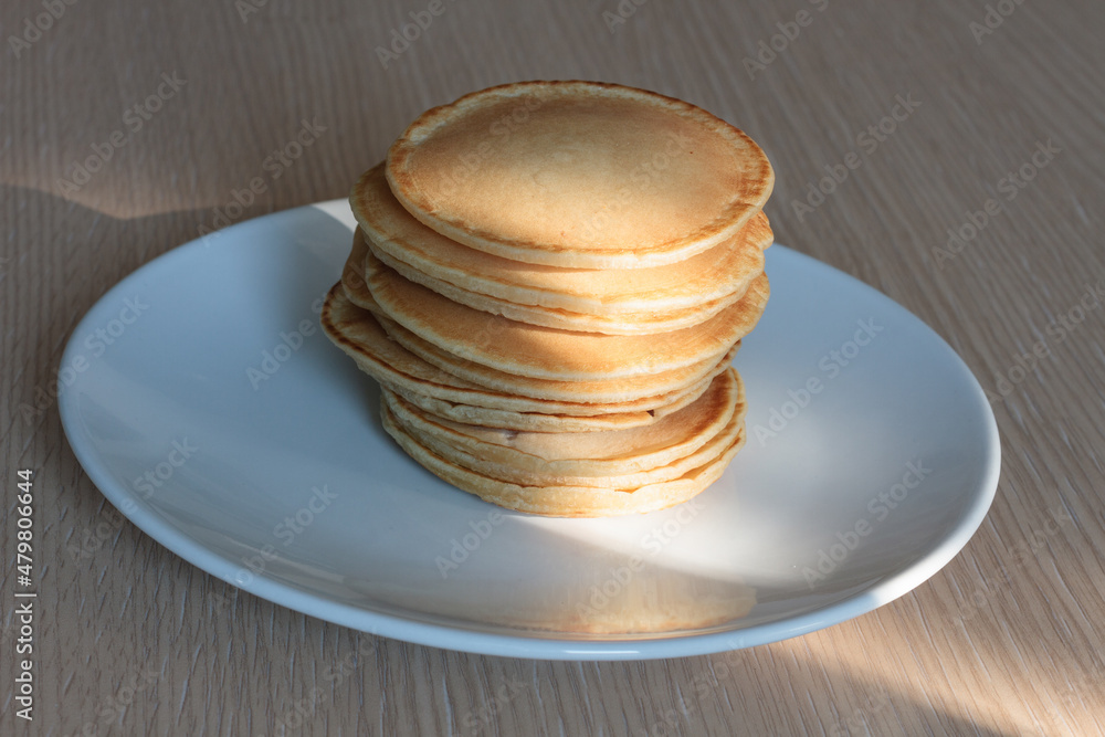 Pile of pancakes on a white dish illuminated by a beam of light Pile of pancakes on a white dish illuminated by a beam of light