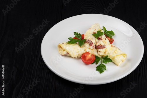 Omelet with Ham and Cheese and fresh vegetable on black wooden background