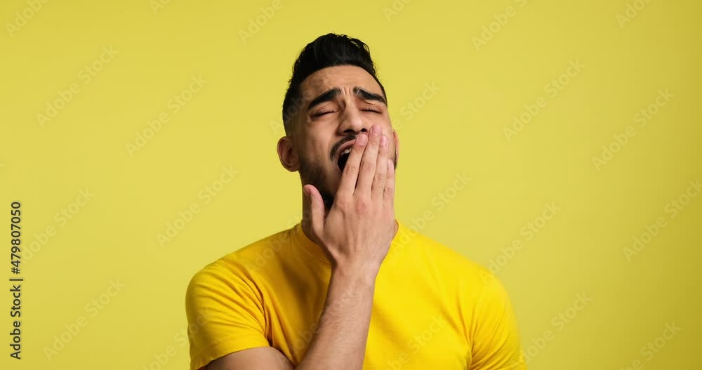 Portrait of tired sleepy man yawning over yellow background Portrait of tired sleepy man yawning over yellow background