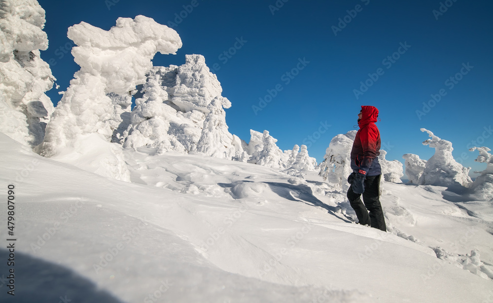 a tourist stands on a snowy mountain in winter in sunny weather