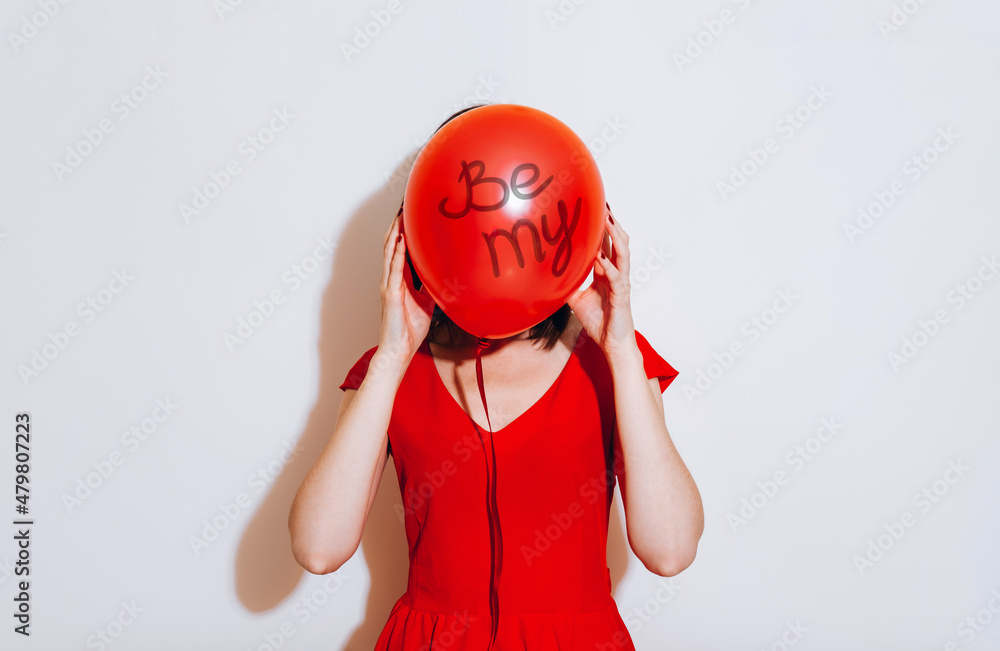 Valentine's Day. Portrait of a beautiful young woman in red dress holding red balloon on white background. Be my Valentine Valentine's Day. Portrait of a beautiful young woman in red dress holding red balloon on white background. Be my Valentine