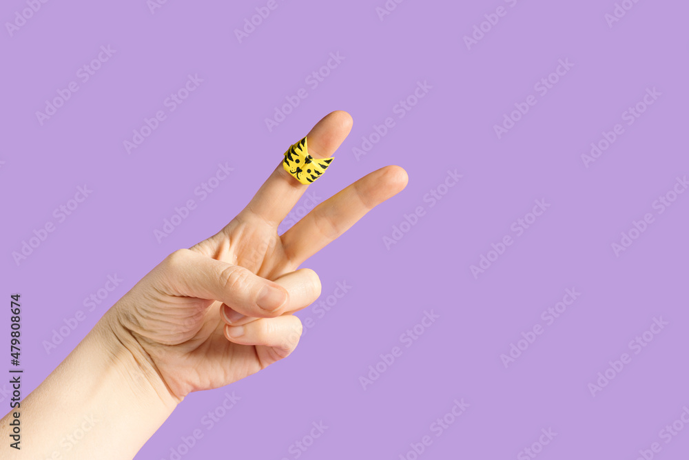 Fingers peace sign wearing origami paper ring with tiger face against pastel background. Minimal Chinese New Year festive celebration concept. Fingers peace sign wearing origami paper ring with tiger face against pastel background. Minimal Chinese New Year festive celebration concept.