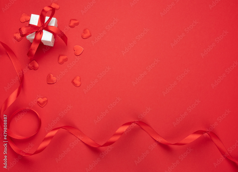 Small gift or engagement ring box and wrapping ribbons on red background. Flat lay composition with copyspace, for Valentine's Day, marriage proposal, birthday, Mother's Day, anniversary or wedding. Small gift or engagement ring box and wrapping ribbons on red background. Flat lay composition with copyspace, for Valentine's Day, marriage proposal, birthday, Mother's Day, anniversary or wedding.