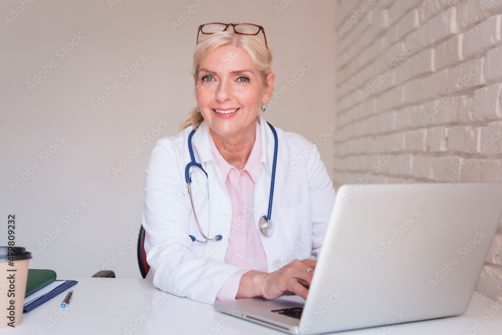 Smiling female doctor working on laptop at the doctor's office Smiling female doctor working on laptop at the doctor's office