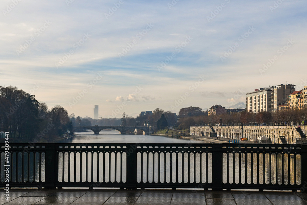 View from Vittorio Emanuele I Bridge over the Po River with  Umberto I Bridge and the silhouette of the Piedmont Region skyscraper in the foggy background in winter, Turin, Piedmont, Italy
