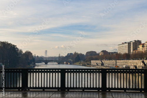 View from Vittorio Emanuele I Bridge over the Po River with Umberto I Bridge and the silhouette of the Piedmont Region skyscraper in the foggy background in winter, Turin, Piedmont, Italy
