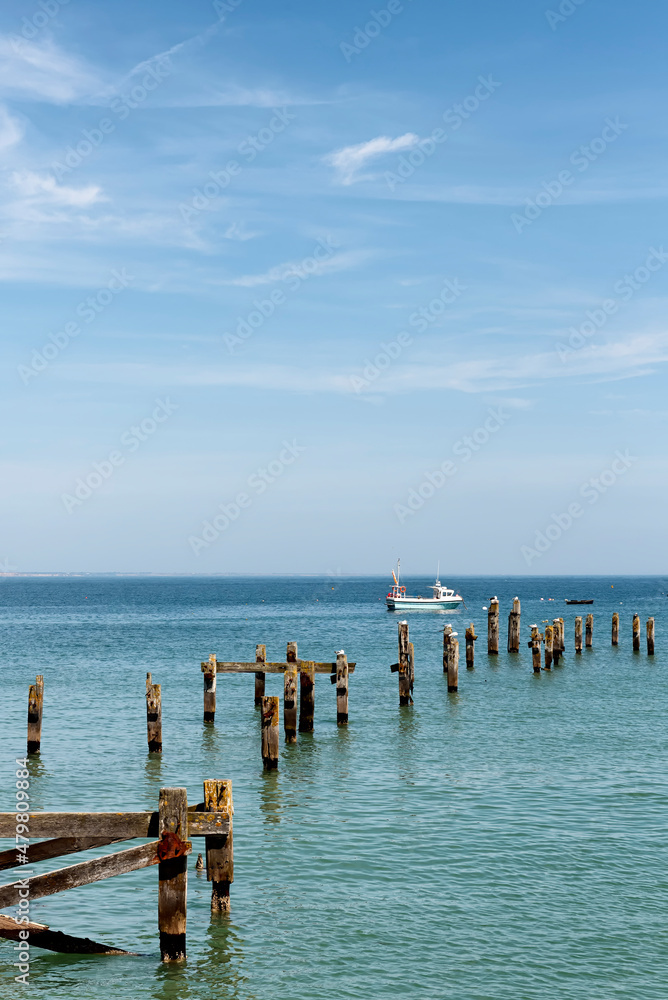 Remains of the old pier in Swanage with a boat in the background