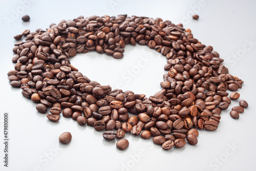 Coffee beans in a heart shape on the gray background. Blured background. Coffee lovers